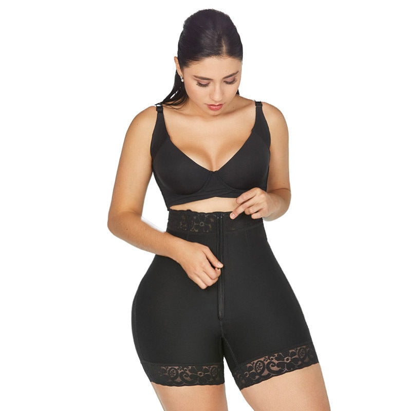 Black high-waist faja shorts worn by a model, front view, fastening the full-length front zip, with a lace-trimmed waistband and lace-trimmed leg hems